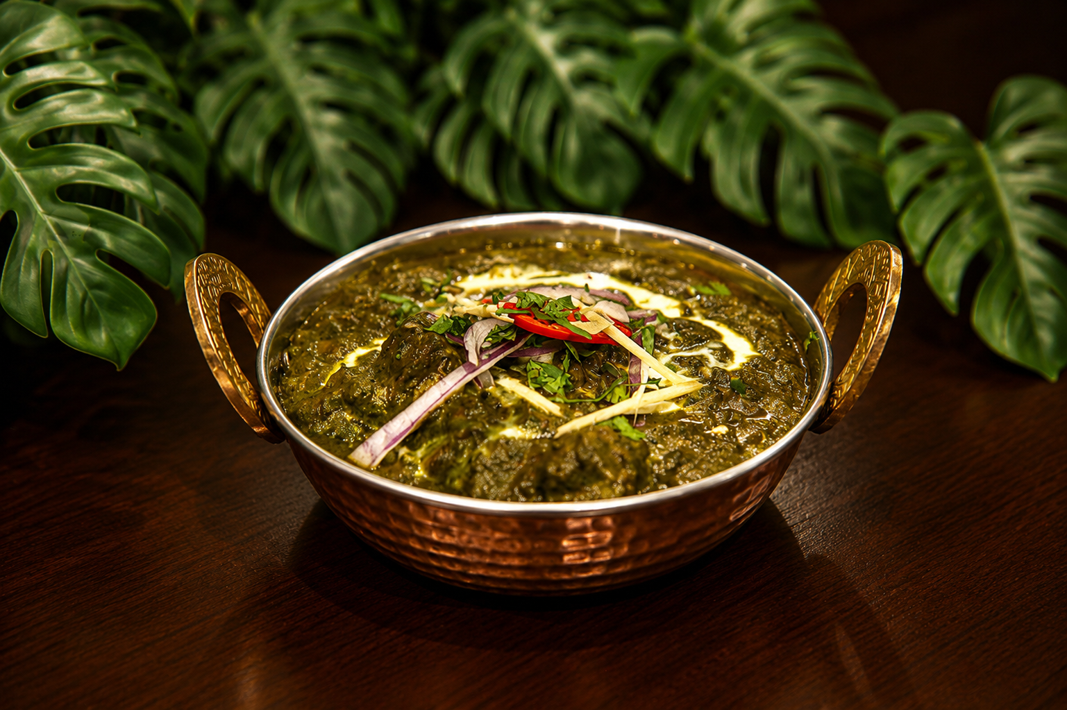 Palak paneer in a copper kadai with a cream swirl, red onion, ginger julienne and red chilli