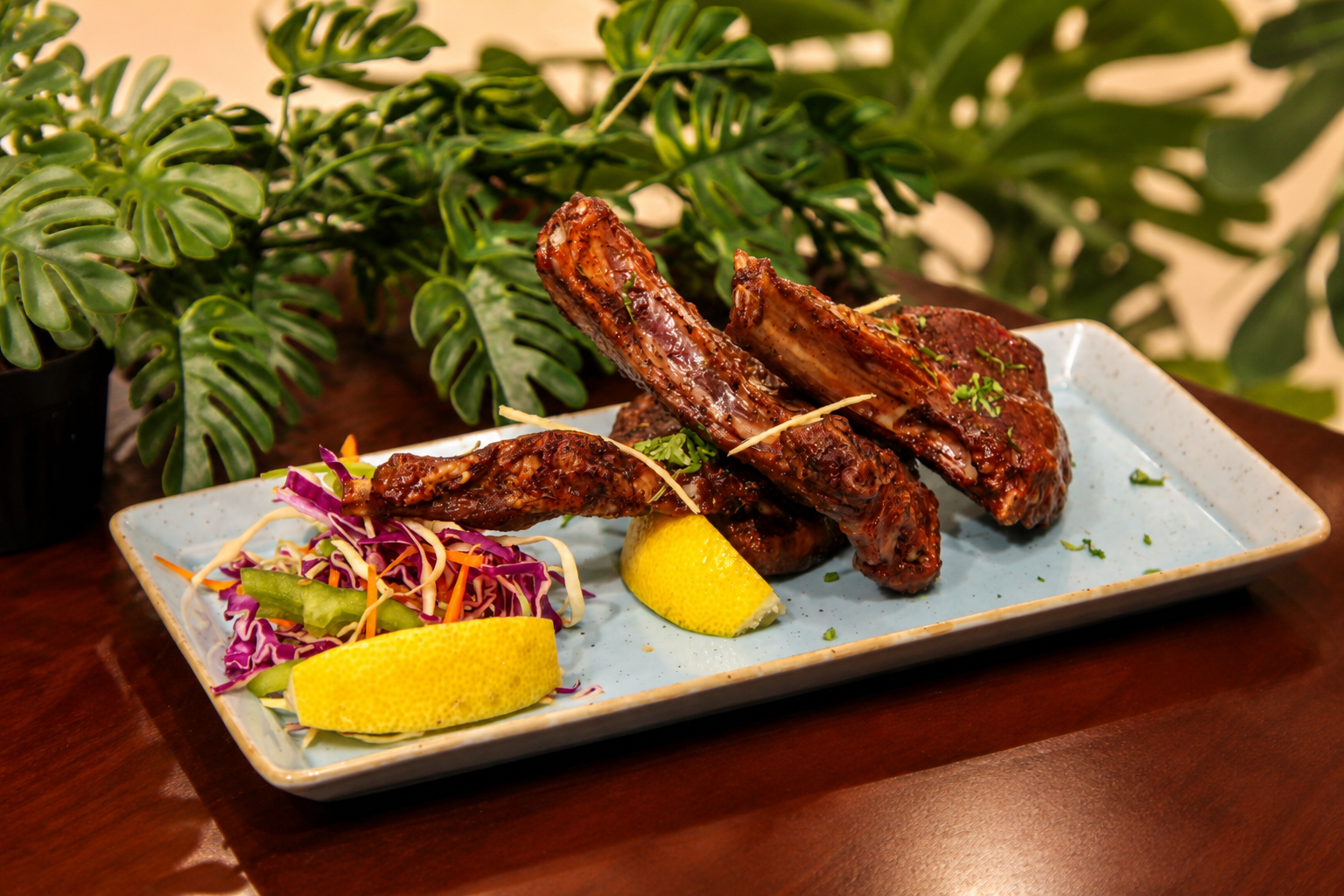 Chargrilled lamb chops with slaw and lemon wedges on a pale blue plate